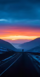 a man on a road near mountains in the evening