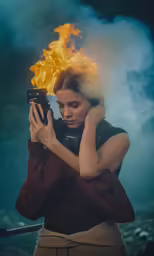 the woman holds a camera and lights on fire