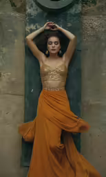 a young woman is posing against the stone wall