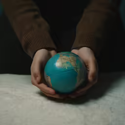a person holding an old blue earth globe
