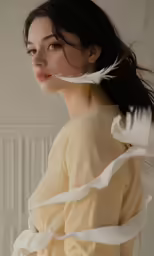 a woman standing wearing a white dress and feathers flying