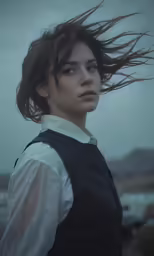 a girl with long hair standing near the ocean
