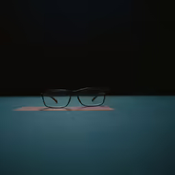 two pairs of glasses are laying on a blue surface
