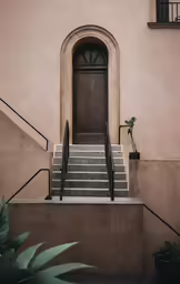 the steps lead up to a door with plants below