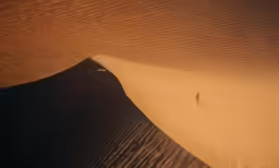 a lone person is alone among the dunes in the desert
