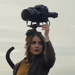 the woman is holding a camera on a tripod