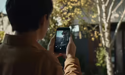 a young boy standing in front of a building with his cellphone