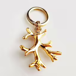 a close up of a gold key chain,a gold colored metal animal keychain on a white surface
