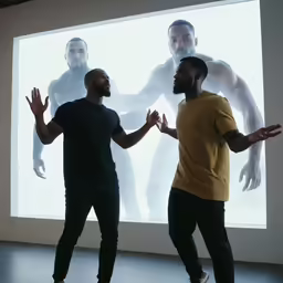 two men are talking while standing in front of a video