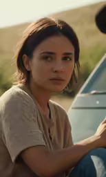 a young woman sitting by the side of her car