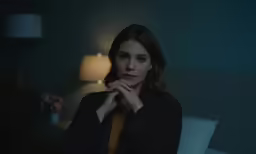 a beautiful young lady sitting on top of a bed in a dark room
