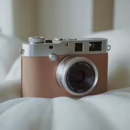 a camera laying on a bed with a white blanket