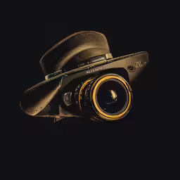 an old camera and hat sitting on the ground