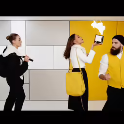 a man and a woman standing in front of a wall holding smart phones
