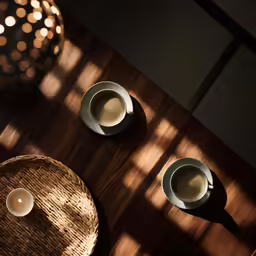 a table with two cups, one coffee cup and a lit candle