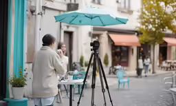 the woman is taking a photo in front of a table with an umbrella on it