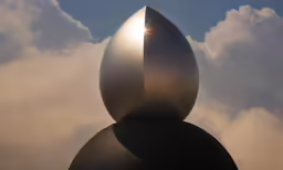 the sun shining through the clouds behind a sculpture