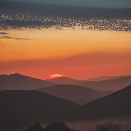 a scenic view of a sunset and distant mountains