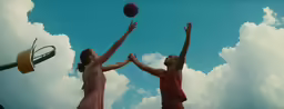 two girls reaching up to grab a basketball