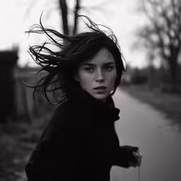a woman is walking on the street while holding onto her hair