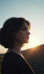 a woman standing outside with the sun setting behind her