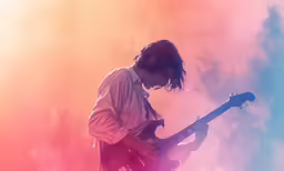 the guitarist in concert looks down at his guitar