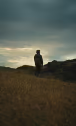 a person walking across a dry grass covered field