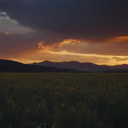 the sunset is shown over mountains in a field