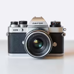a silver and black camera sitting on top of a table