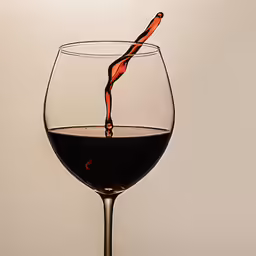 a glass of red wine is being filled with wine