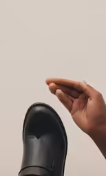 a hand reaching up into the air next to black shoe