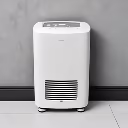 white portable air purificator sits against a grey wall