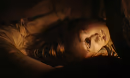a close up of a young girl lying on her stomach in the dark