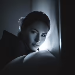 the lady is posing near the wall with a lit up light on her