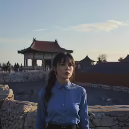 a woman standing in front of a stone wall and building
