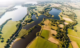 an aerial shot of an empty river and grass fields