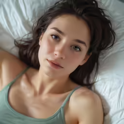 a woman laying on top of a bed next to a pillow