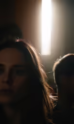 a woman in a dark room staring into the light