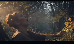 a woman in the woods has her face slightly tilted to the side