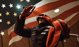 a man in a motorcycle helmet holding his cell phone in front of an american flag