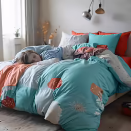 a child is asleep in his bed with blue and orange sheets