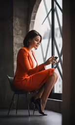 the woman is using her cellphone in an orange dress