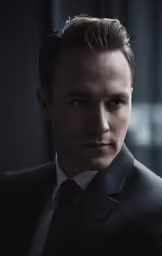 a man in a suit and tie stares into the camera