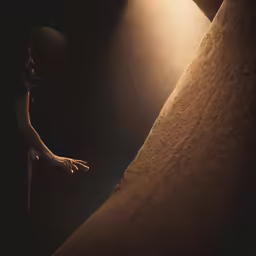 a woman standing in the dark with her hands out towards a light