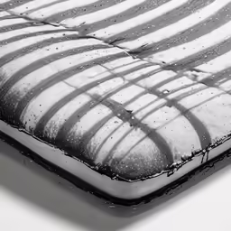 black and white photo of an unmade bed with the sheets covered