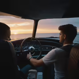 a man sits in a car as the sun sets
