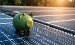a green piggy bank sitting on top of a solar panel