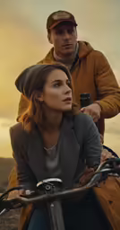 man on bicycle next to woman with camera