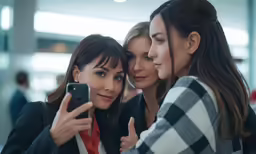 two women holding their cell phones together while looking at them