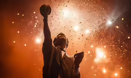 a person in brown jacket with hands raised on top of fireworks